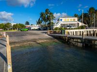 a view of the water from a dock with cars driving on it in front of a building