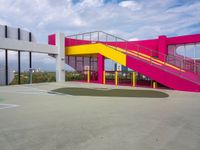 a colorful basketball court with a big stairwell on one floor and yellow railings on the other side