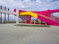 a colorful basketball court with a big stairwell on one floor and yellow railings on the other side