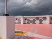 a white building and cement wall with a yellow fire hydrant and a dark sky