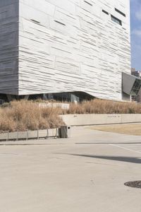 an outdoor area with benches, chairs and a building in the background with tall buildings