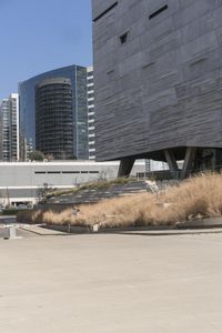 an outdoor area with benches, chairs and a building in the background with tall buildings