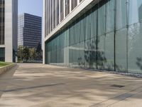 the shadow of a man walks across the sidewalk as he crosses an empty street in front of glass and concrete buildings