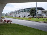 a street under an overpass is lined with stairs and grass near a building with stairs on the side