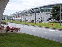 a street under an overpass is lined with stairs and grass near a building with stairs on the side
