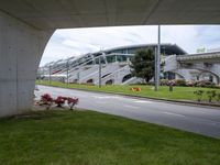 a street under an overpass is lined with stairs and grass near a building with stairs on the side