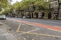 a city street has two sidewalks that are marked in red and white arrows with cars parked on the side