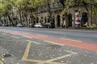 a city street has two sidewalks that are marked in red and white arrows with cars parked on the side