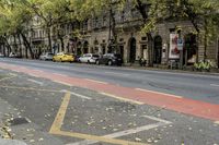 a city street has two sidewalks that are marked in red and white arrows with cars parked on the side