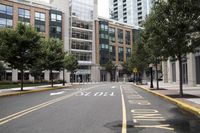 people are crossing the street in an area with many tall buildings and trees on both sides