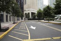 people are crossing the street in an area with many tall buildings and trees on both sides