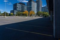 buildings in a city area, as seen from a parking lot in autumn, with a car parked nearby