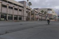an empty street with palm trees and buildings in the background near the tracks that lead up to the train