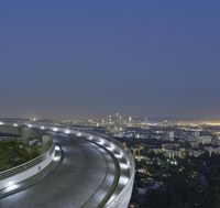 freeway with city lights along the edge at night with traffic in the background of photograph