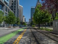 the green paint is painted on a bike path in front of an office building and large, trees