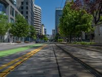 the green paint is painted on a bike path in front of an office building and large, trees