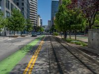 the green paint is painted on a bike path in front of an office building and large, trees