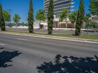 a car sitting at an empty street underneath a overpass overhang that contains a train stop, and cars and a pedestrian