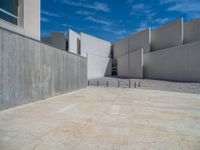 the gray concrete walls of a building have a line of steps on the left side