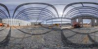 a fish eye view of a construction area with steel arches and workers working on the ground