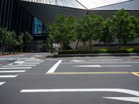 a city street with white arrows marked in the parking spaces on both sides and trees, along with an outdoor seating area with glass buildings