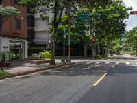an empty road with some tall buildings on it and trees in the middle of the street