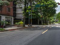 an empty road with some tall buildings on it and trees in the middle of the street