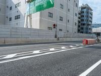 two people on the bike are crossing the road at an intersection, one has their hand on the red barrier, while the other is holding the bike and another behind her