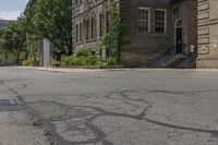 a sidewalk with a fire hydrant between two old buildings in an urban area with lots of trees