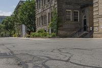 a sidewalk with a fire hydrant between two old buildings in an urban area with lots of trees