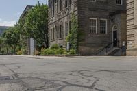 a sidewalk with a fire hydrant between two old buildings in an urban area with lots of trees