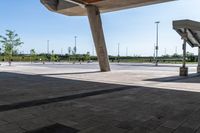 a man sitting on his skateboard under an overpass above concrete pavement and pillars