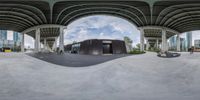 a mirror shot is seen over an empty skate park ramp with people sitting on it