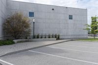 empty parking lot with two window on building next to bushes and trees, next to street light