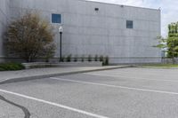 empty parking lot with two window on building next to bushes and trees, next to street light