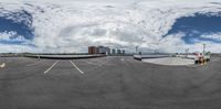 a picture of a fisheye lens of some sort of parking lot area with clouds overhead