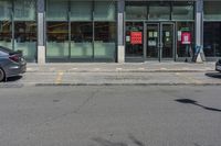 a storefront with two cars parked outside the window with parking meters in front of it