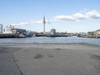 an empty asphalted road next to a waterway in the cityscape of a big city