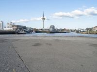 an empty asphalted road next to a waterway in the cityscape of a big city