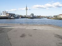 an empty asphalted road next to a waterway in the cityscape of a big city