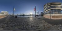 a 360 - view shows a building and water way, and some flags are flying near