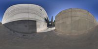 two circular concrete shapes, with a ramp, a building and an empty area in the back ground