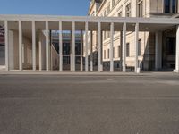 a person wearing a hat on a cell phone while in front of a building with columns and glass doors