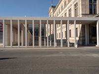 a person wearing a hat on a cell phone while in front of a building with columns and glass doors