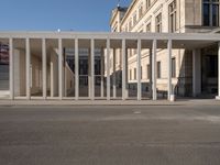 a person wearing a hat on a cell phone while in front of a building with columns and glass doors