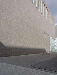 a side street view of the exterior of a building, looking up at the shadow of a wall