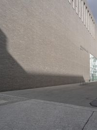 a side street view of the exterior of a building, looking up at the shadow of a wall