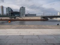 an empty street in the city next to a bridge and city buildings under a cloudy sky