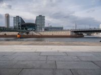 an empty street in the city next to a bridge and city buildings under a cloudy sky