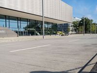 a woman is walking by the modern building on the street with skateboards in hand